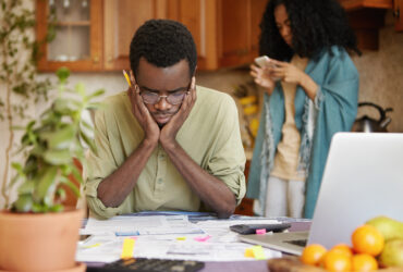 Stressed Young African Male Doing Paperwork At Home, Holding Hands On Head Having Frustrated And Puzzled Look While Reading Notification From Bank In Front Of Him, Failed To Pay Loan In Time